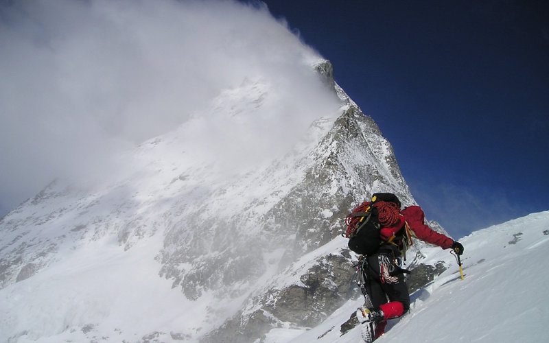 Person climbing a mountain with cloud coverage