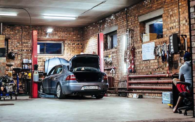 a man is working on a car inside a garage, surrounded by tools and equipment