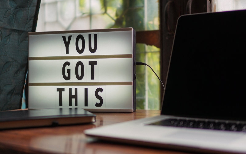 an illuminated electrical sign which displays "you got this" beside a laptop and a cellphone
