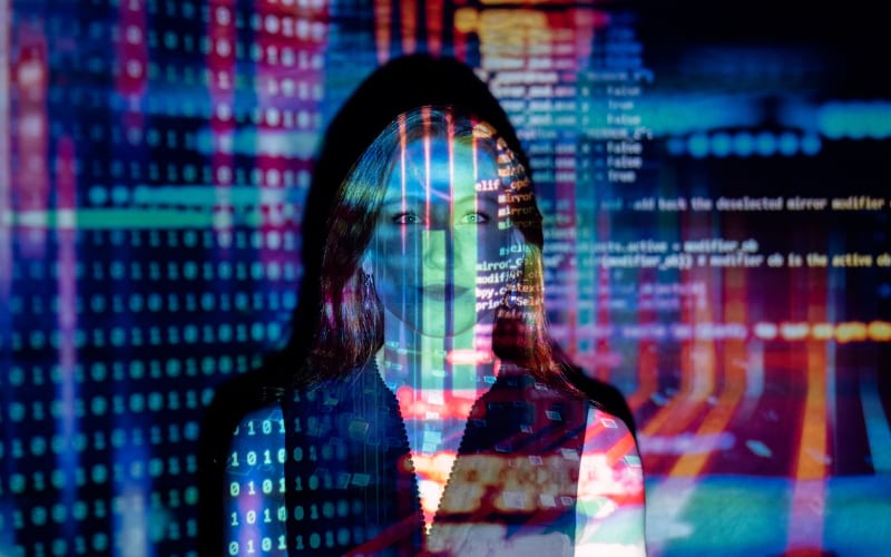 a woman standing with light reflections of binaries and computer data and programming codes