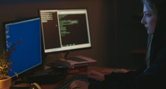 a woman in a hoodie is focused on her work while typing on a computer