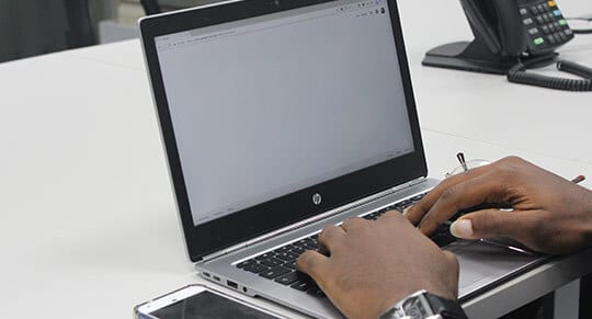 a man using a small hp laptop displaying a white screen while typing in the keyboard