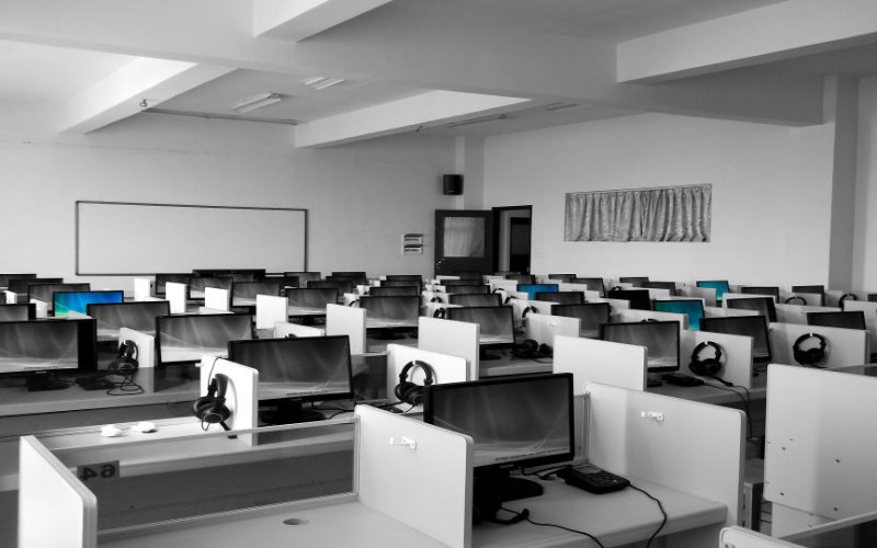 a black and white photo of a classroom featuring several computers arranged on desks