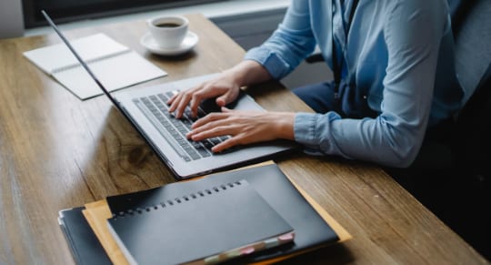 a person focused on typing on a laptop computer, with hands positioned over the keyboard