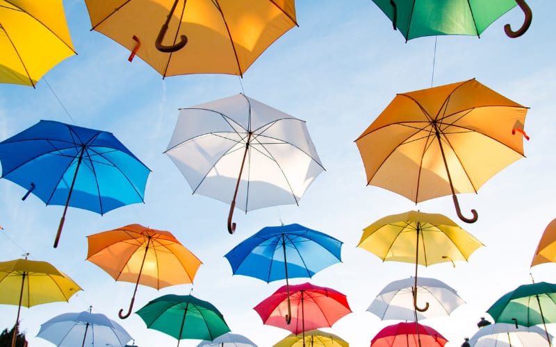 various umbrellas with different colors hanged on top using a metal rope