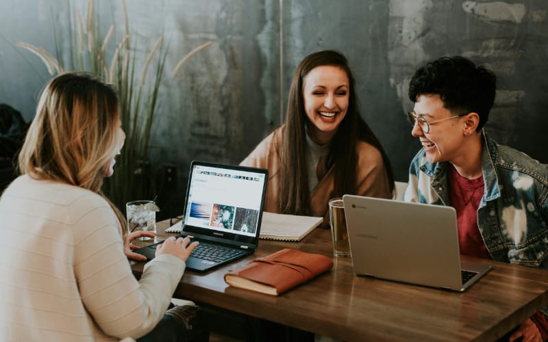 three women laughing together while on their work inside a work station